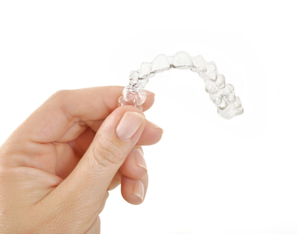 Hand displaying Invisalign aligner